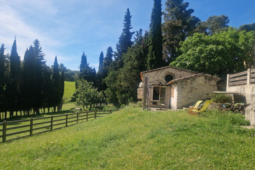 Le gîte Les Cascailles, bâtisse en pierre bordée de cyprès
